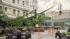 An outdoor patio with seating, planters, and a view of a building in the background.
