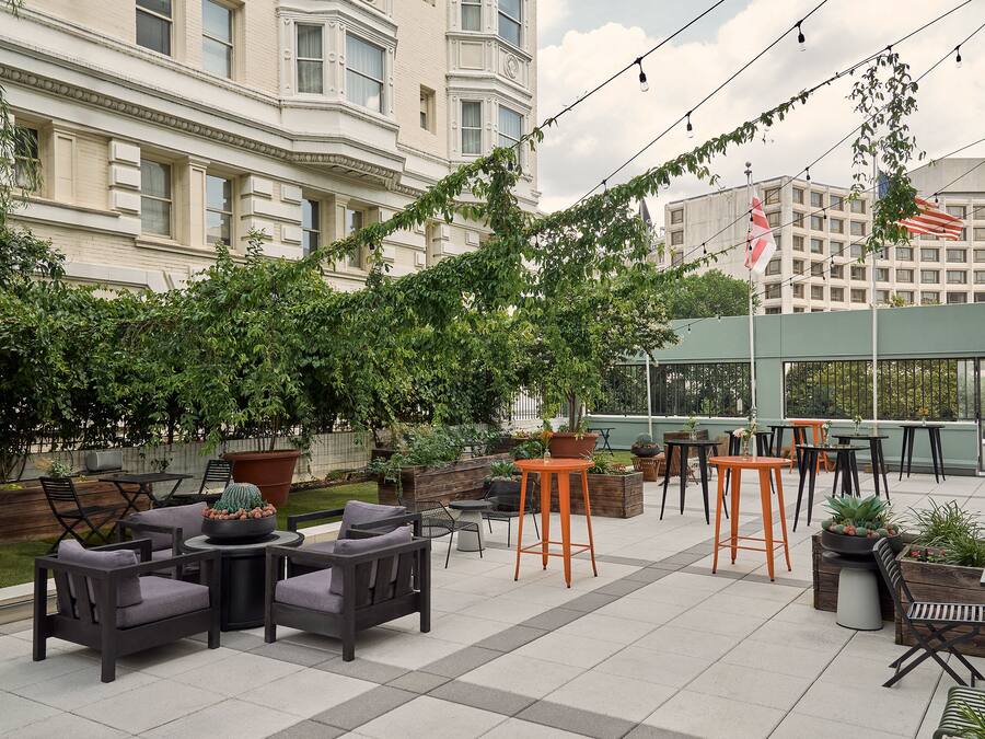 An outdoor patio with seating, planters, and a view of a building in the background.