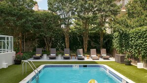 A swimming pool with a 6 ft depth marker, surrounded by grass, trees, and lounge chairs.