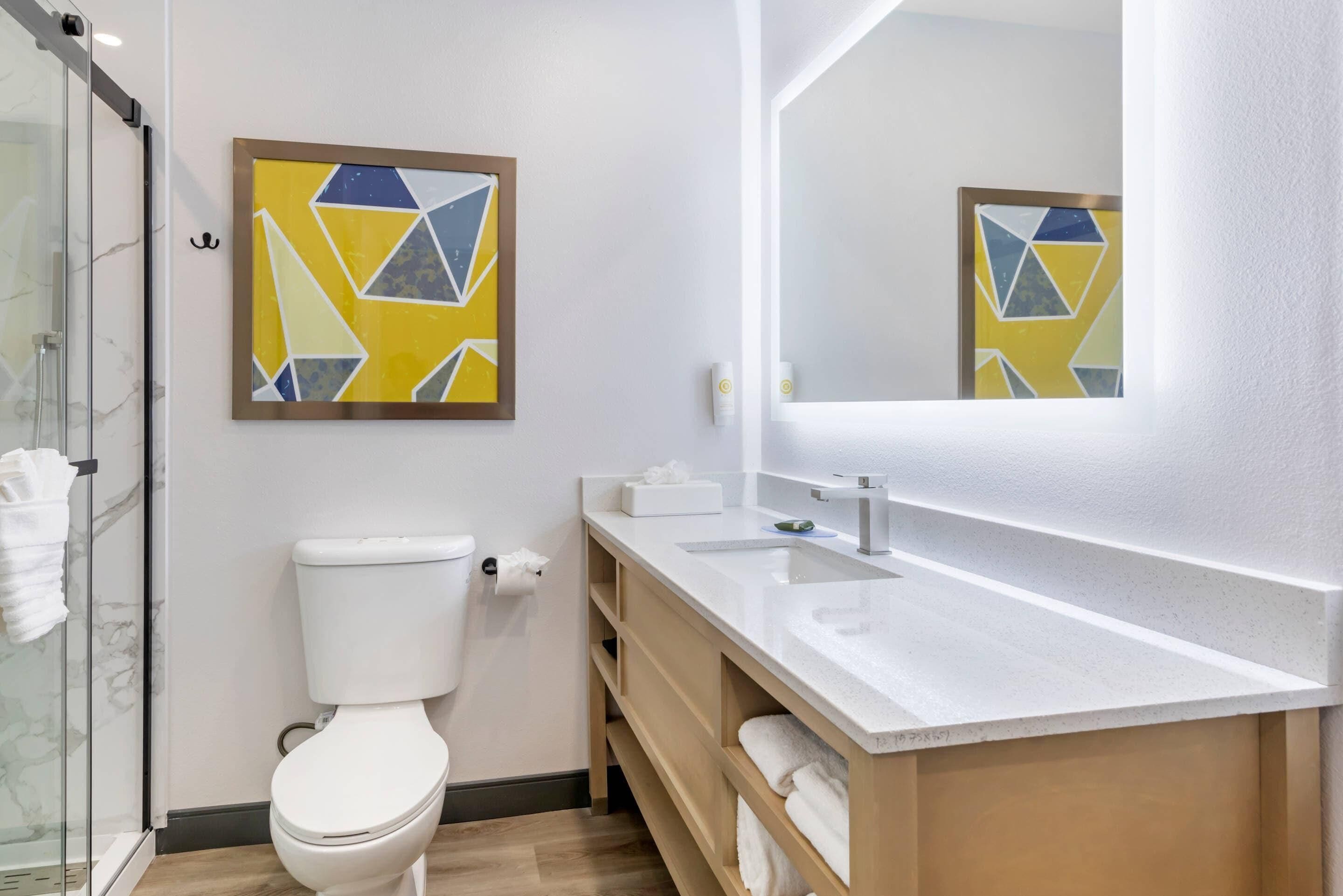 A modern bathroom with a toilet, sink, and glass shower enclosure.