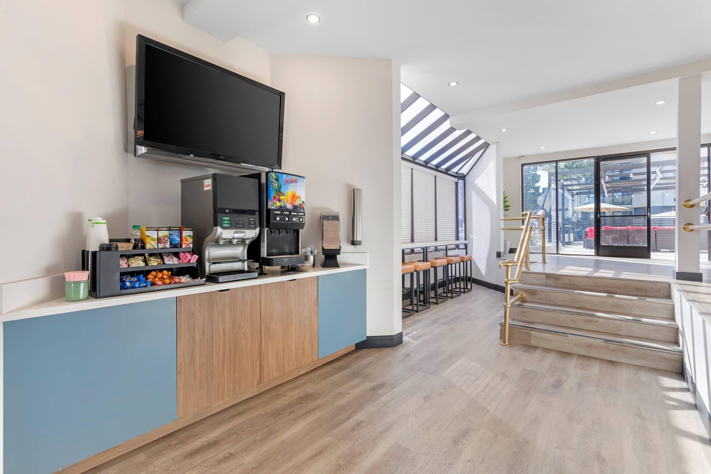 A modern kitchen area with a coffee machine, a flat-screen TV, and a barista station.