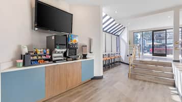 A modern kitchen area with a coffee machine, a flat-screen TV, and a barista station.