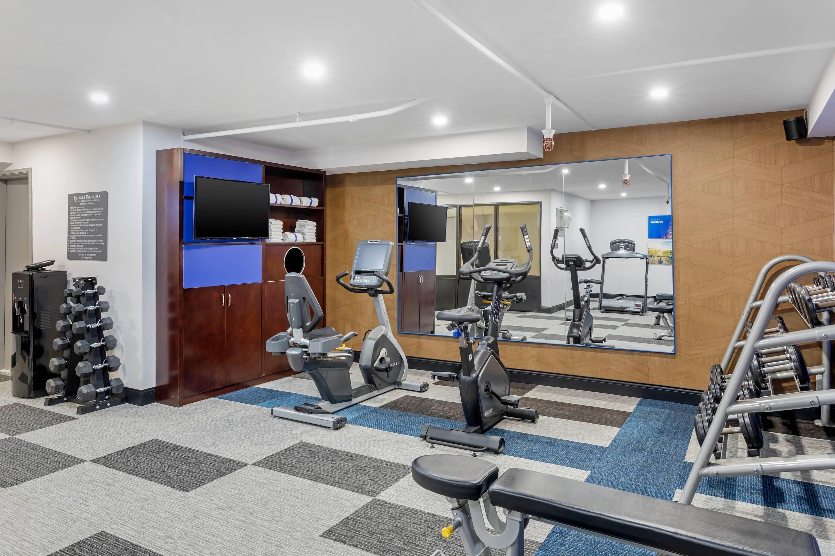A gym with exercise equipment, a television, and a mirror.