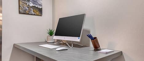 A modern desk with a desktop computer, keyboard, mouse, and a small potted plant.