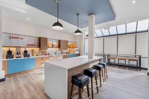 A modern kitchen with a central island, bar stools, and a view of the city through large windows. - Comfort Inn & Suites Irvine Spectrum (Lake Forest)