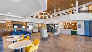 A spacious lobby with a blue sofa, yellow chairs, and a reception desk. - Comfort Inn & Suites Irvine Spectrum (Lake Forest)