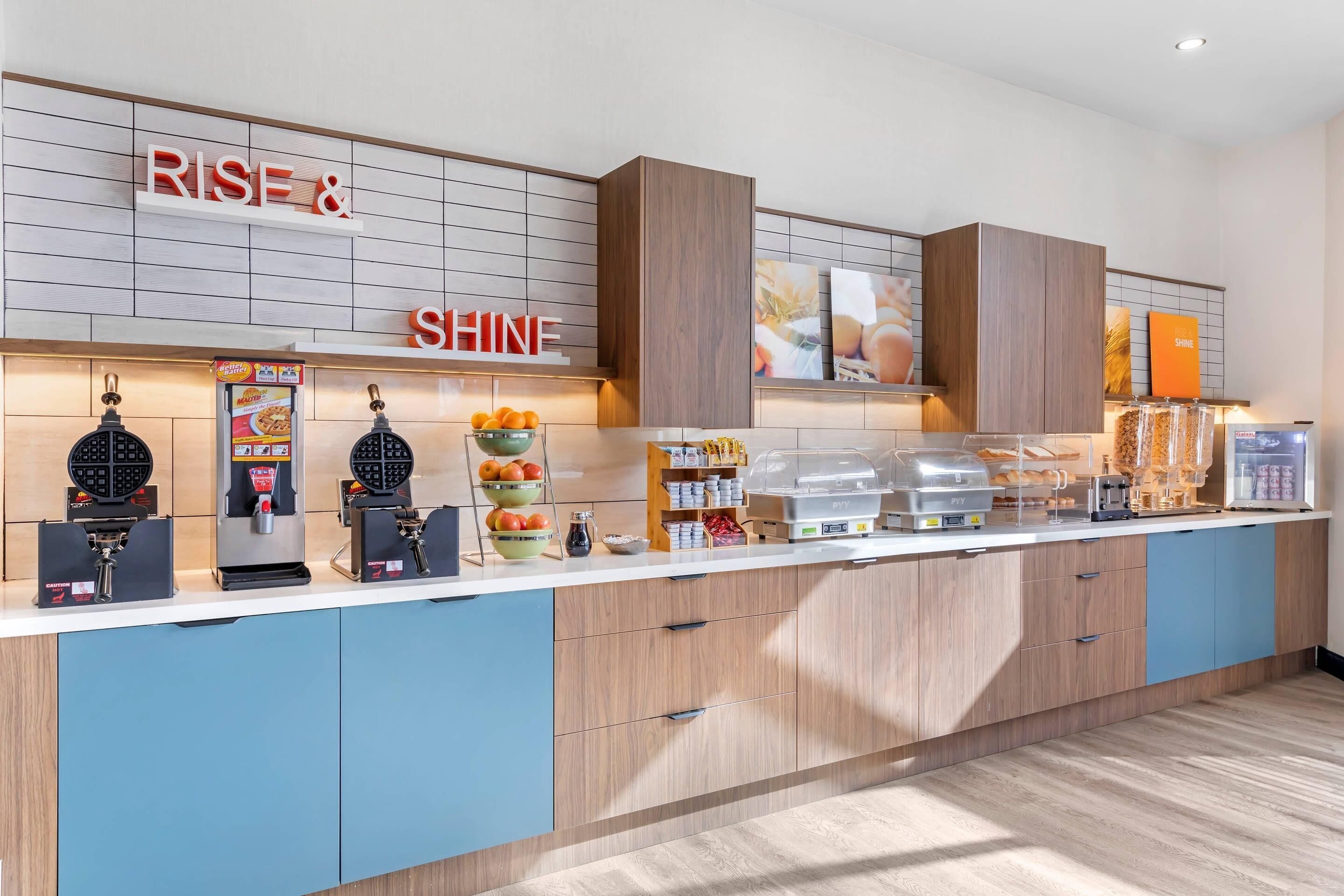A breakfast bar with waffle makers, a coffee machine, and a fruit bowl.
