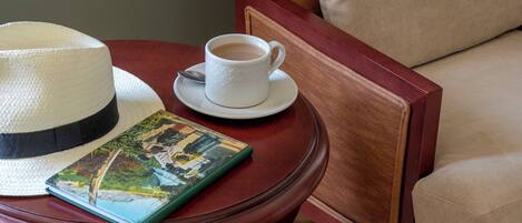 Una mesa de madera con un sombrero, una taza y un libro.