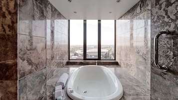A modern bathroom with a freestanding bathtub, a window with a city view, and a shower area.