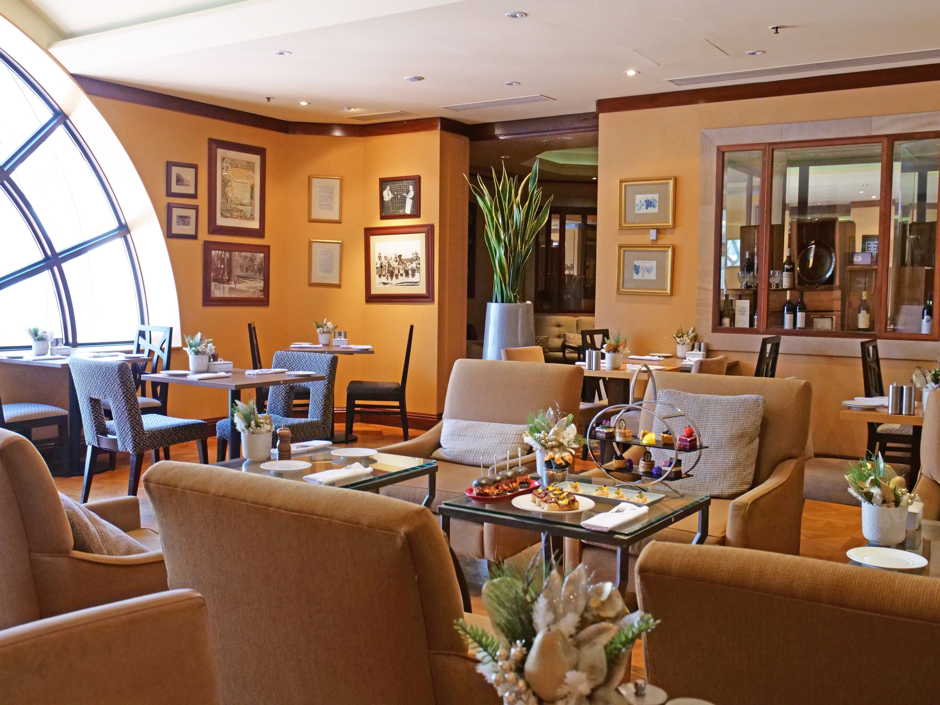 A hotel lobby with a seating area, dining tables, and framed artwork on the walls.