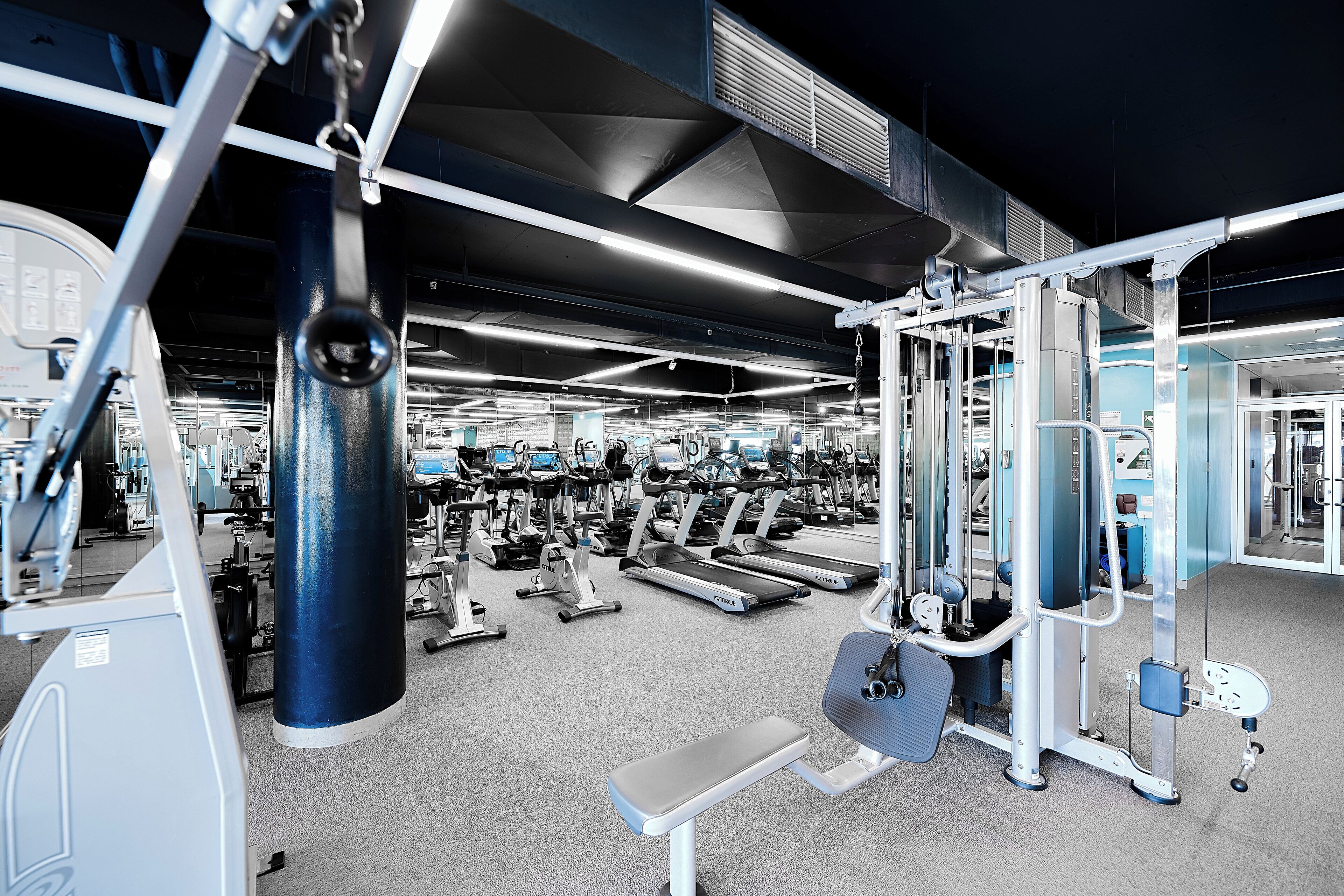 Un gimnasio con diversos equipos de ejercicio, incluyendo cintas de correr y máquinas de pesas.