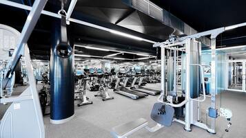 Un gimnasio con diversos equipos de ejercicio, incluyendo cintas de correr y máquinas de pesas.