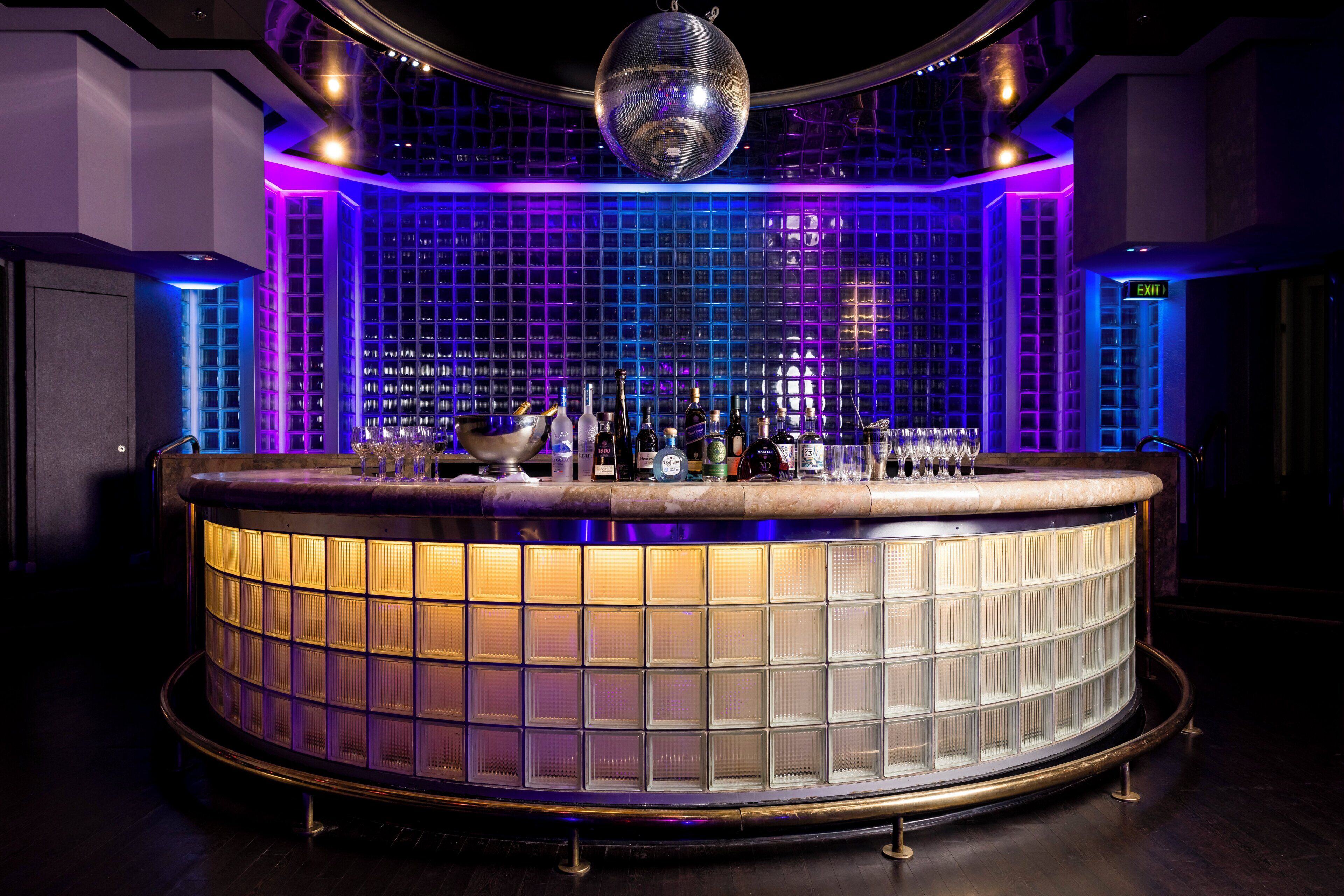 A bar area with a circular counter, a disco ball, and a grid-patterned wall.
