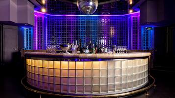 A bar area with a circular counter, a disco ball, and a grid-patterned wall.