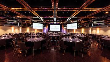 A conference room with multiple tables, chairs, and large screens displaying 'Intercontinental Adelaide'.