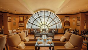 A spacious dining area with a large central table, surrounded by comfortable seating, and a distinctive arched window above. - InterContinental Adelaide by IHG (Adelaide)