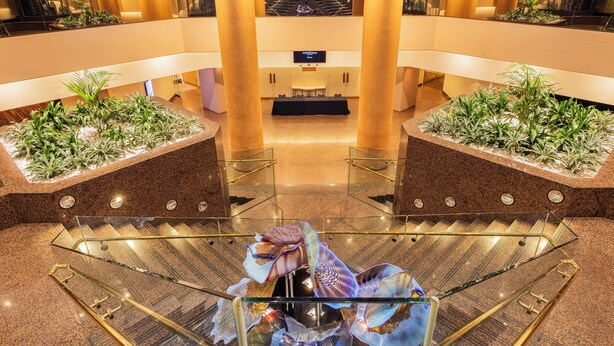 A hotel lobby with a glass elevator, a reception desk, and decorative plants. - InterContinental Adelaide by IHG (Adelaide)