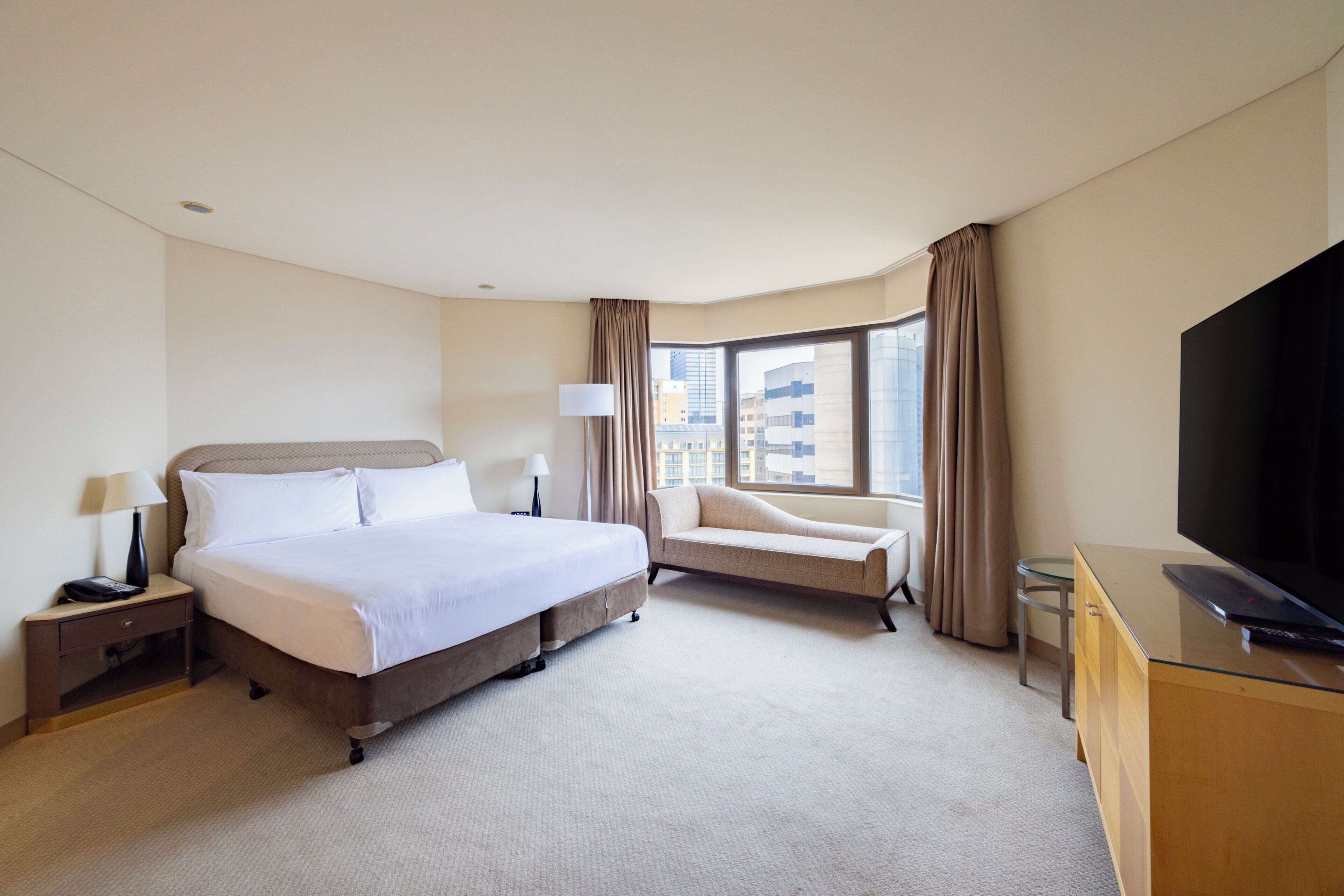 A hotel room with a large bed, a sofa, a TV, and a desk.