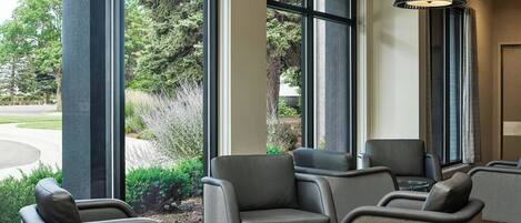 A modern lobby with large windows, comfortable seating, and a stylish pendant light.