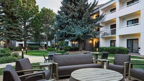 A courtyard with outdoor seating, including sofas and a round table, surrounded by trees and a building with balconies. - Courtyard by Marriott Boulder (Boulder)