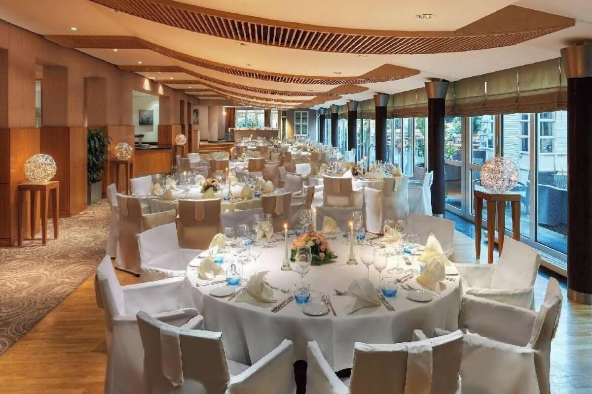 A banquet hall with round tables, white tablecloths, and chairs.