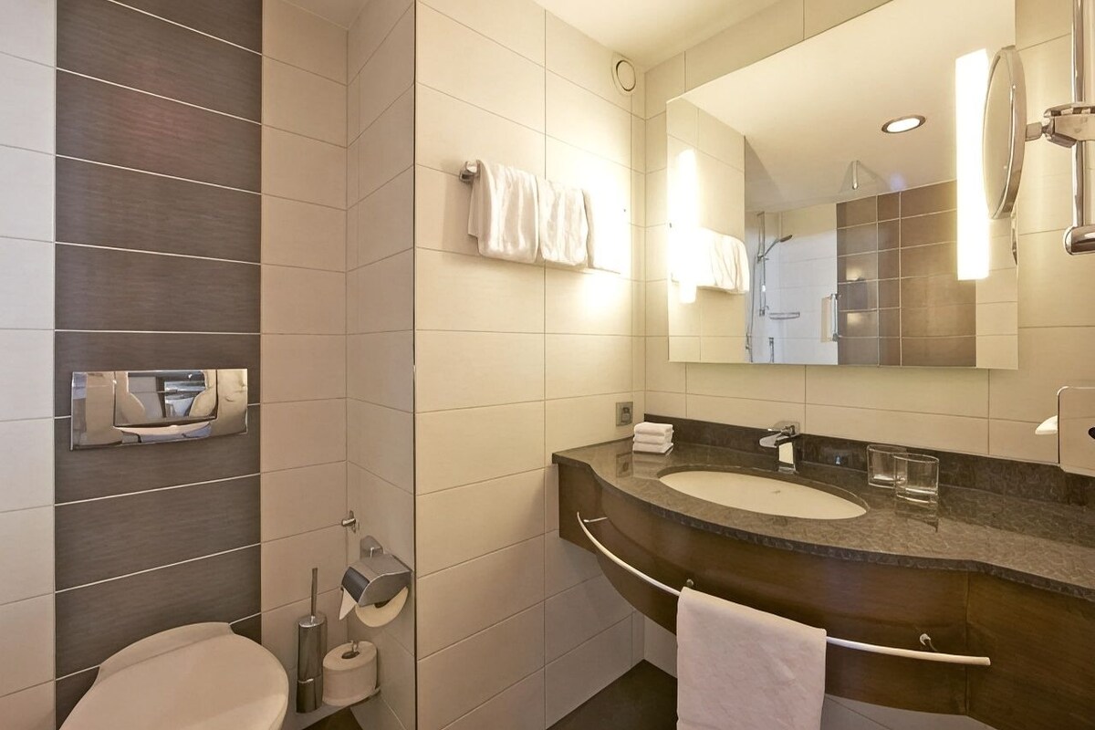 A modern bathroom with a toilet, sink, and mirror.