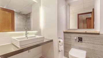 A modern bathroom with a large mirror, a white sink, and a toilet.