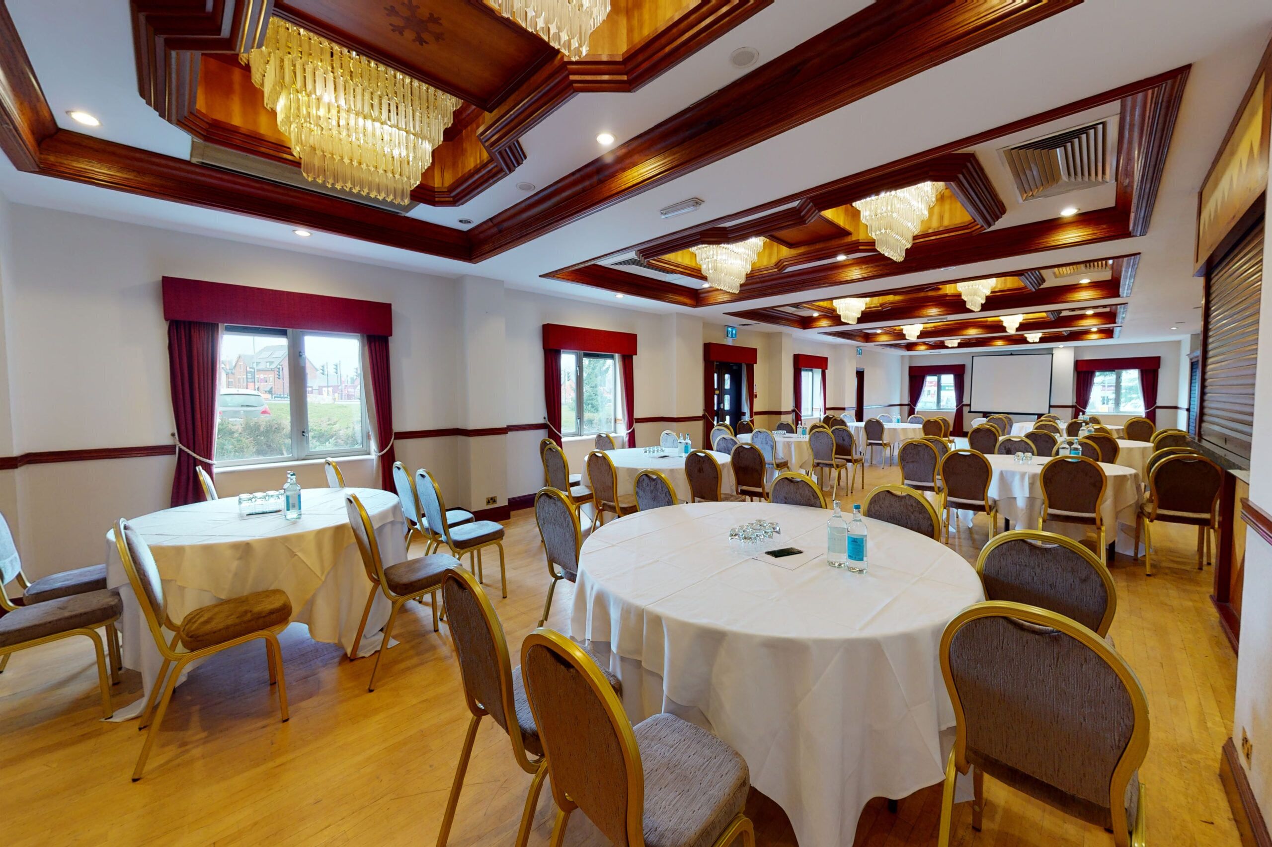 A conference room with round tables, chairs, and chandeliers.