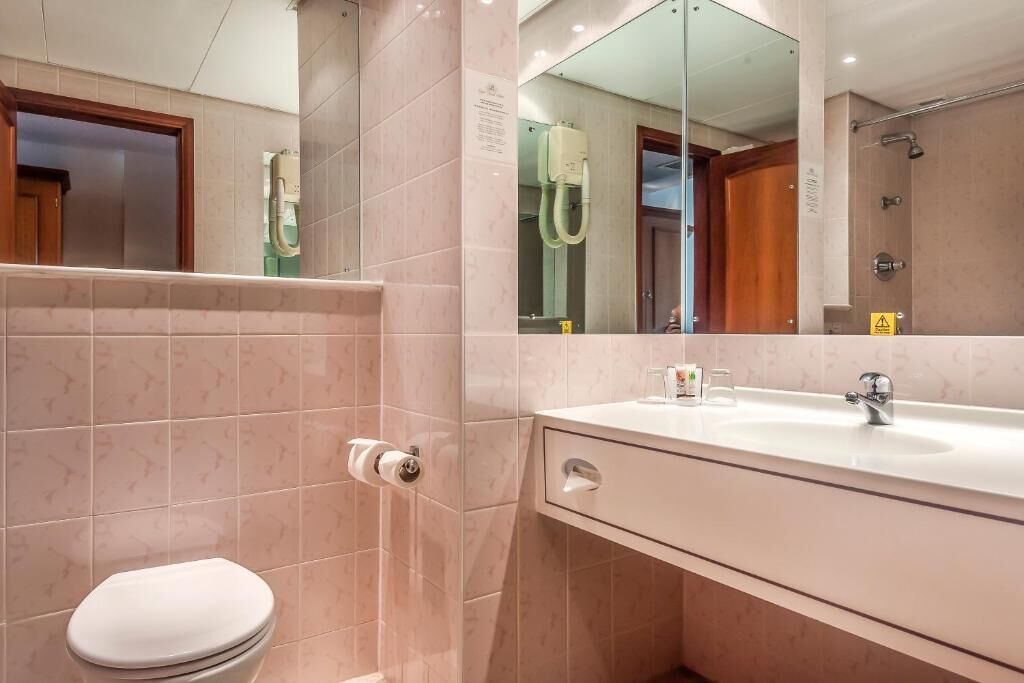 Une salle de bain avec des toilettes, un lavabo et un miroir.