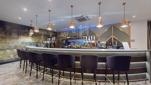 A bar area with a counter, multiple bar stools, and a variety of bottles and glasses. - The Coppid Beech Hotel (Bracknell)