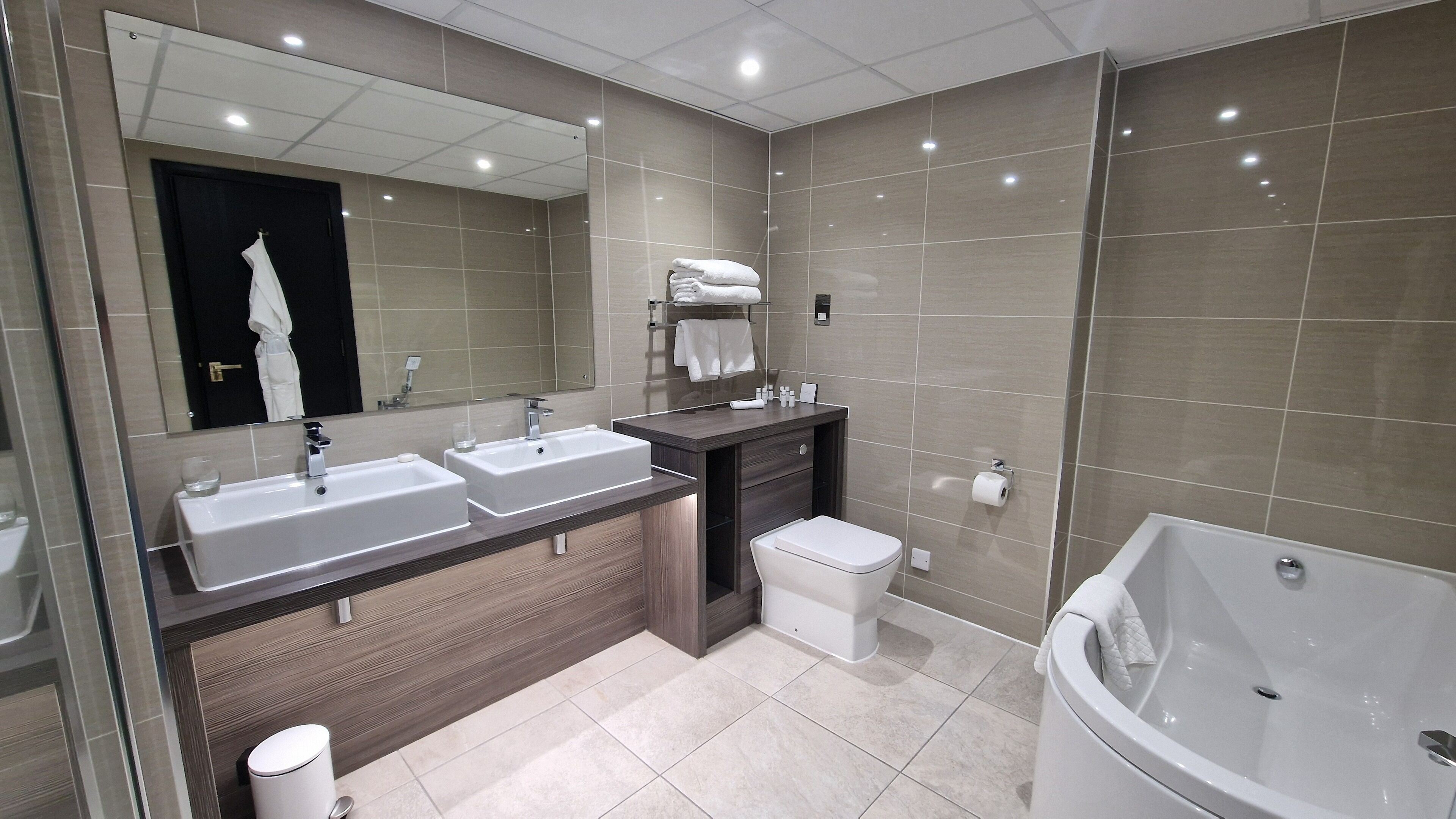A modern bathroom with two sinks, a toilet, and a bathtub.