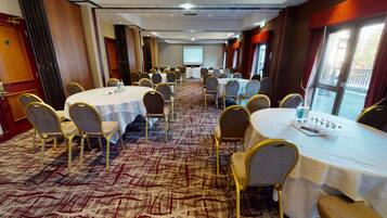 A conference room with round tables, chairs, and a carpeted floor.