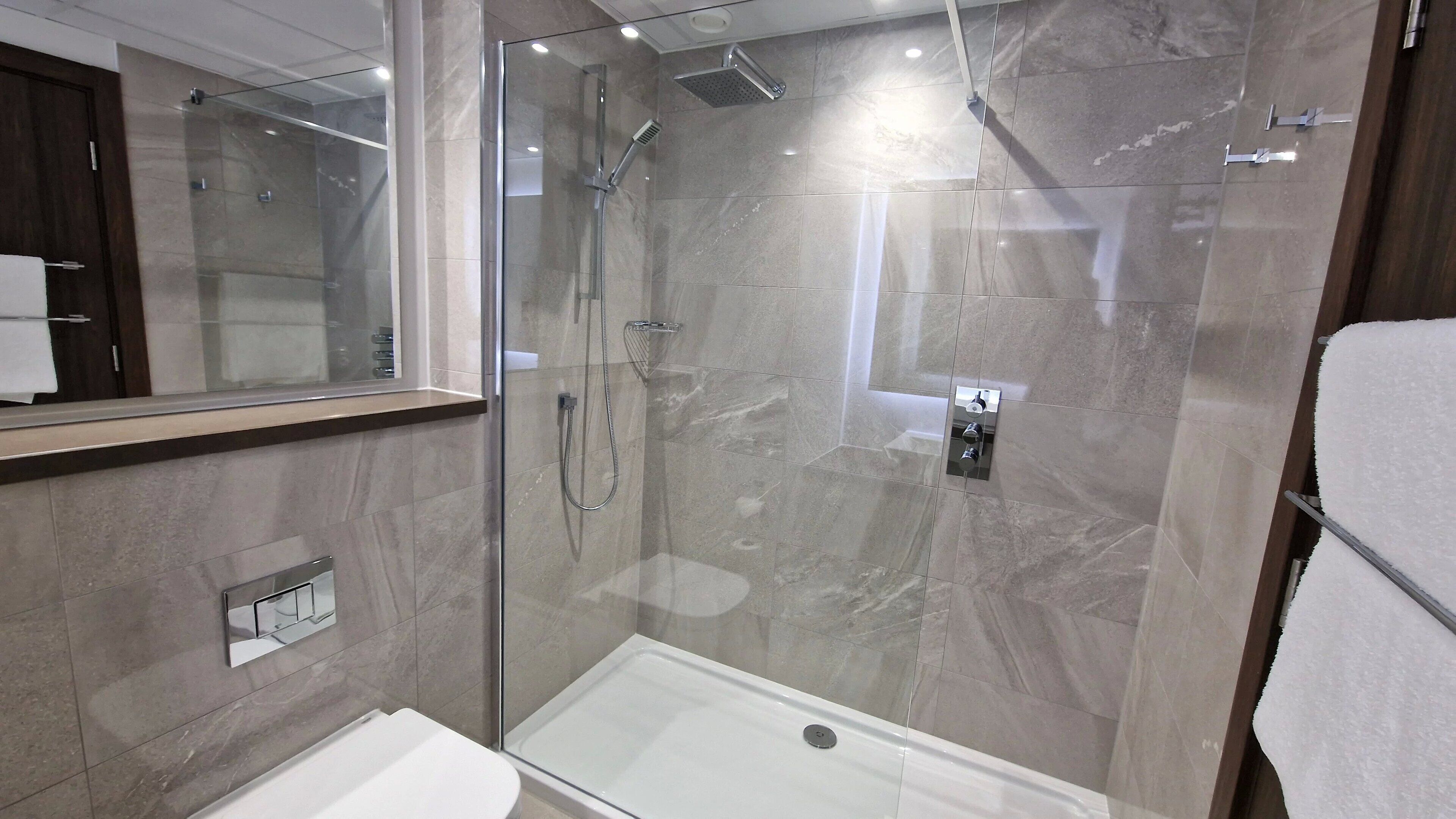 A modern bathroom with a glass-enclosed shower, a white sink, and a mirror.