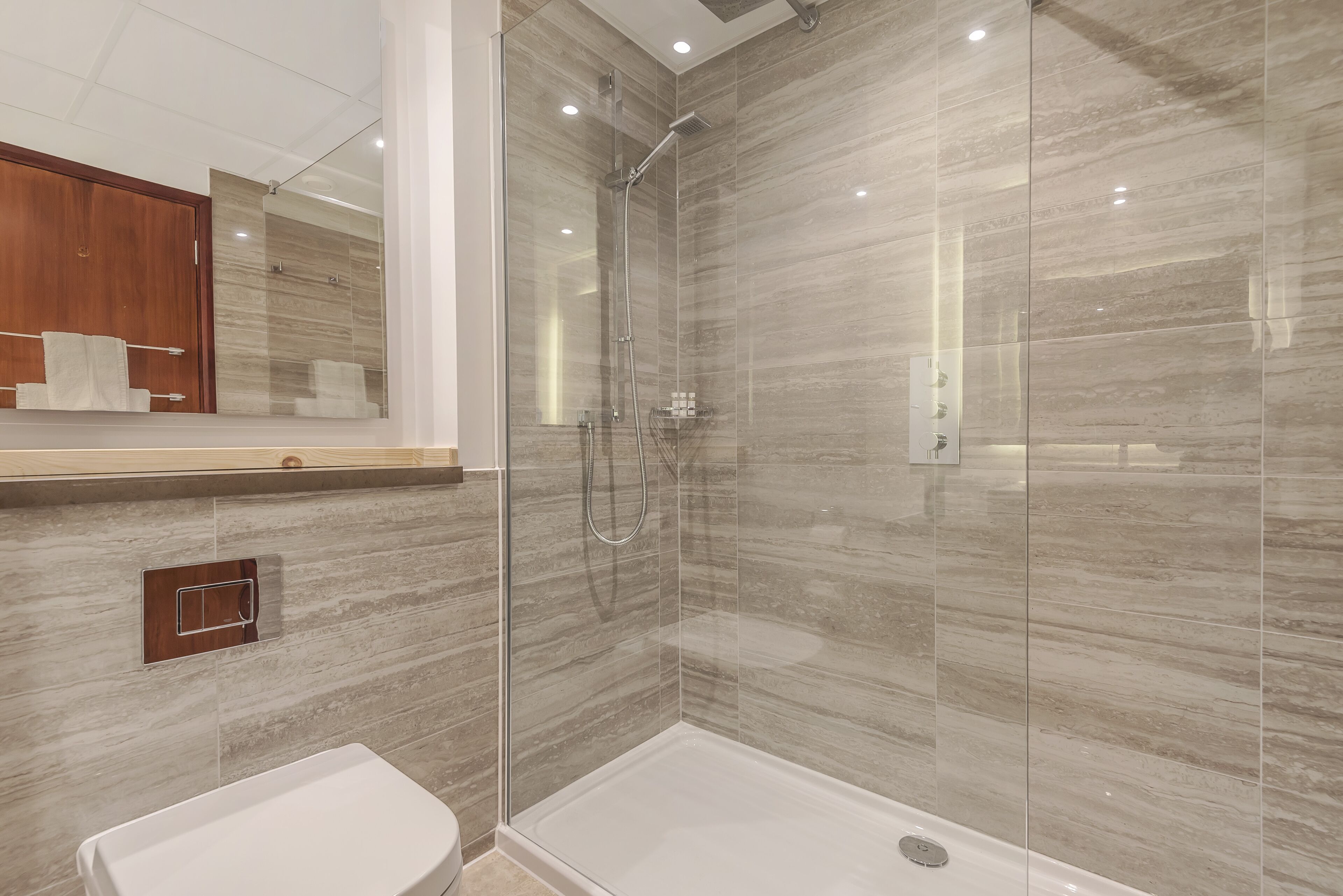 A modern bathroom with a glass-enclosed shower, a wooden vanity, and a white sink.