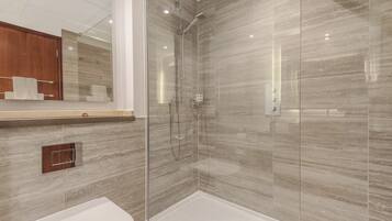 A modern bathroom with a glass-enclosed shower, a wooden vanity, and a white sink.