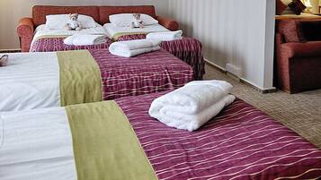 Habitación de hotel con dos camas, cada una con un oso de peluche, una silla, una mesa y una lámpara.