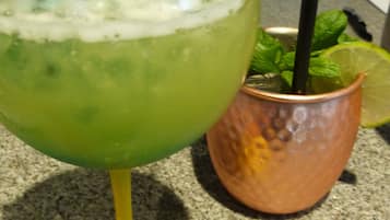 A cocktail glass with a lime wedge and mint leaves on a granite countertop.