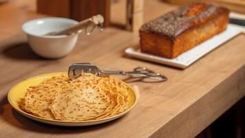 Una mesa de madera con una fuente de crepas y una hogaza de pan.