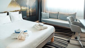 Una habitación de hotel con cama, sofá, escritorio y silla.