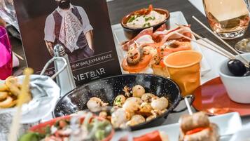 Een eettafel met eten, een drankje en een poster.