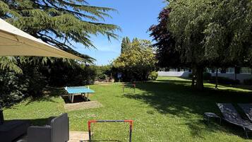 A grassy outdoor area with a patio, a table, and a goalpost.