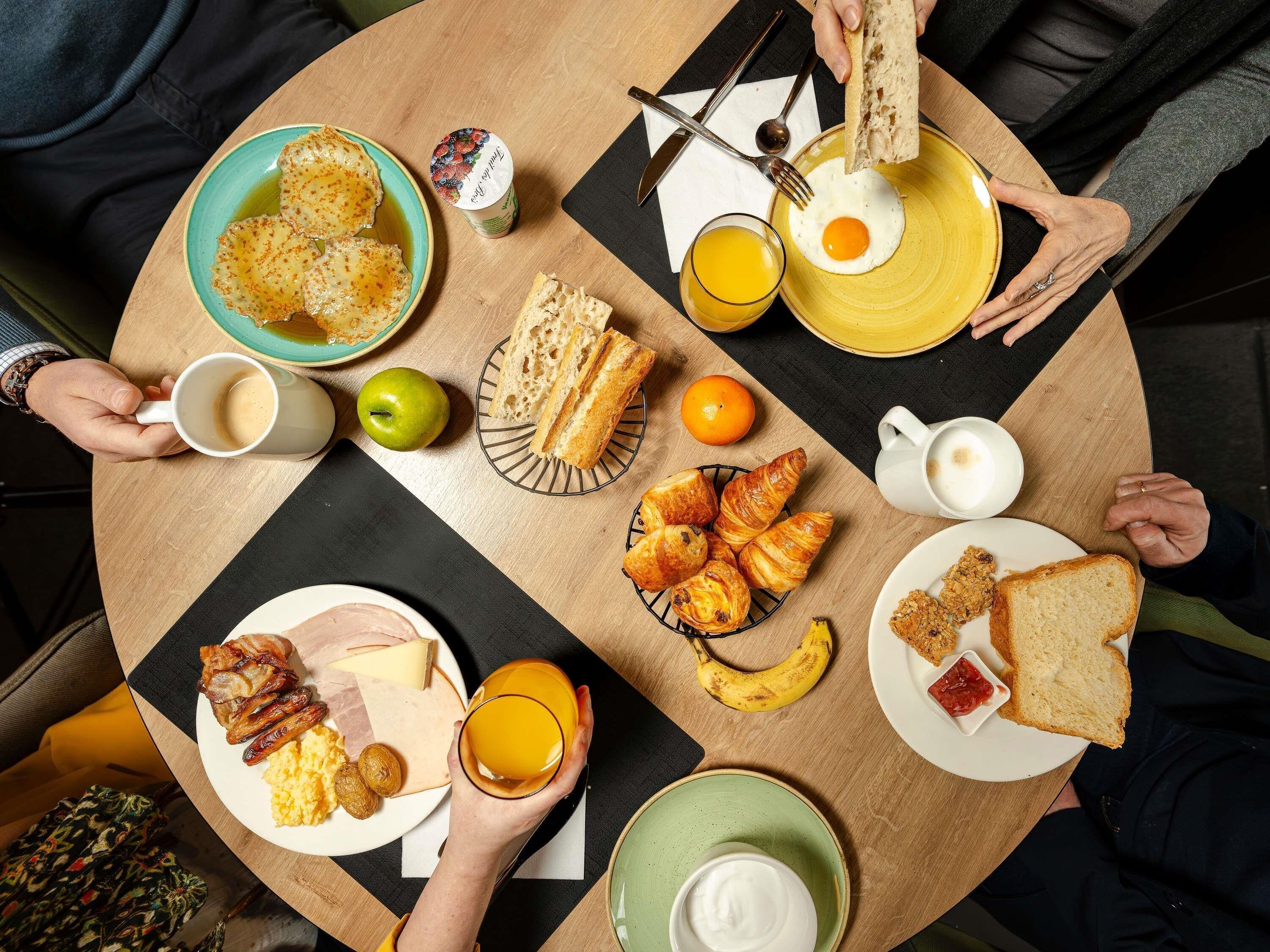 A round dining table with various breakfast items including eggs, toast, pastries, and fruit.