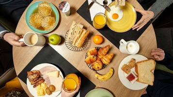 A round dining table with various breakfast items including eggs, toast, pastries, and fruit.