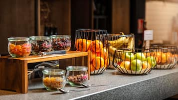 A buffet counter with various food items in glass containers and wire baskets, including fruits and nuts.