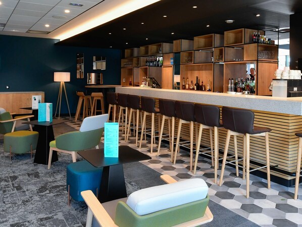 A bar area with stools, a counter, and shelves with bottles.