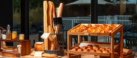 Un buffet de petit-déjeuner comprenant du pain, des viennoiseries et diverses garnitures.