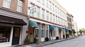 A row of historic buildings with classic architecture, including a sign for 'Kings Courtyard Inn' and 'Roberto Coin' on the ground floor. - Kings Courtyard Inn (Charleston)