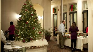 A Christmas tree in a dining area with tables set for a meal. - Kings Courtyard Inn (Charleston)