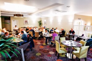 Enjoy dining in style with round tables and comfortable seating for groups, set with fine china and glassware.
