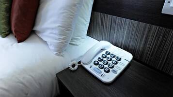 Habitació d'hotel amb llit, almoinades, una taula de nit i un telèfon.